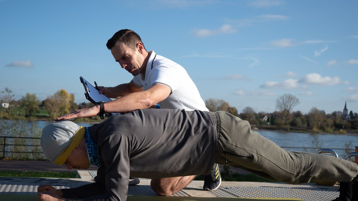 Christian Roller korrigiert im Personal Training die Haltung einer Kundin im Unterarmstütz