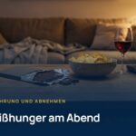Heißhunger am Abend: Schokolade, Chips und ein Glas Rotwein auf dem Couchtisch vor dem Sofa